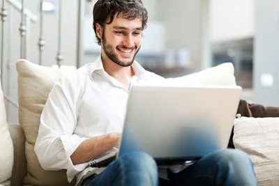 Mann mit Notebook auf einem Sofa